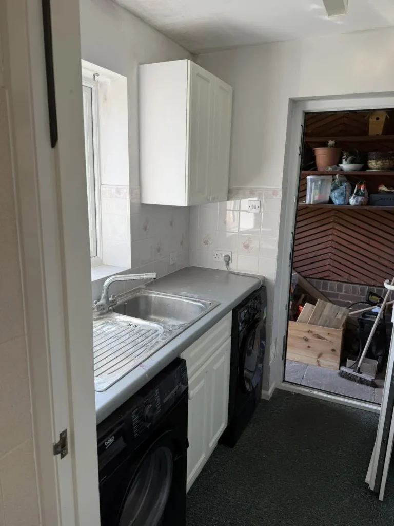 The original utility room before renovation, with dated units and tiling