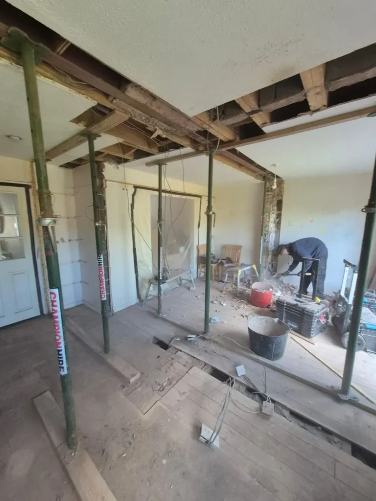 Strip-out stage with acrow props shoring the masonry and timber joists before the load-bearing walls came out